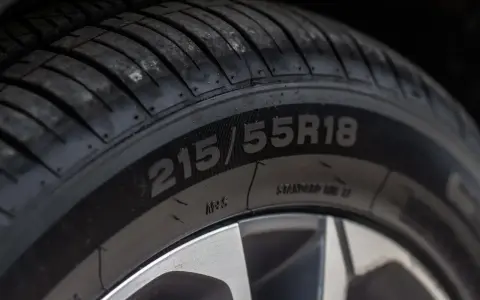 Zbliżenie na oponę z widocznymi oznaczeniami 215/55R18. To ważne oznaczenia opon, które informują o jej rozmiarze i konstrukcji.