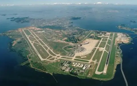 Lotnisko Rio de Janeiro z lotu ptaka, z pasami startowymi i terminalem, otoczone wodą i zielenią.