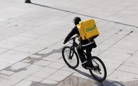 Kurier Glovo na rowerze z charakterystyczną żółtą torbą. Praca w dostawie to jego codzienne wyzwanie.