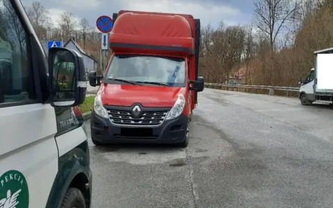 Czerwony bus Renault na drodze, obok pojazd inspekcji. Może to być związane z wnioskiem o wypis z licencji transportowej.