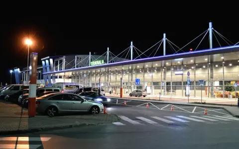 Nocne lotnisko Kraków-Balice, Terminal A. Samochody czekają na pasażerów, a światła tworzą niepowtarzalny klimat.