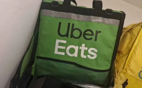 Zielona torba Uber Eats, obok żółtej torby Glovo. Taki widok może oznaczać potencjalne uber eats zarobki.