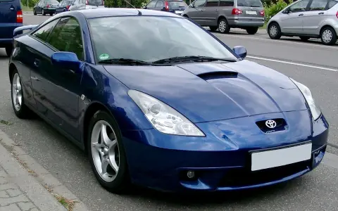 Błękitna Toyota Celica, jeden z najpiękniejszych aut, parkuje na poboczu drogi.