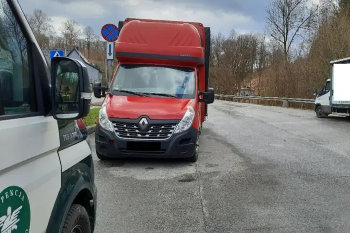 Czerwony bus Renault na drodze, obok pojazd inspekcji. Może to być związane z wnioskiem o wypis z licencji transportowej.