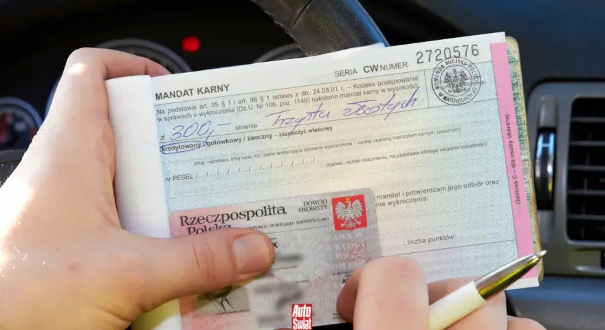 Dłoń trzyma mandat karny i dowód osobisty.