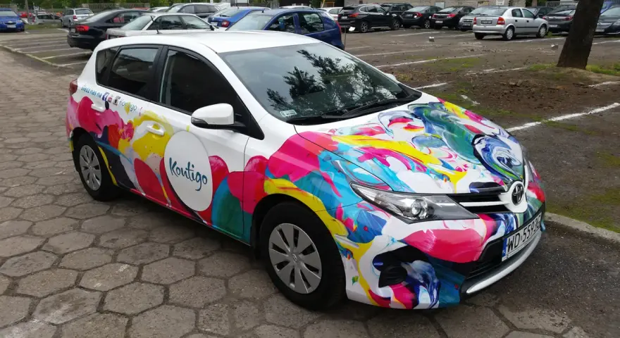 Kolorowe oklejone samochody z logo "Koutigo" na parkingu.