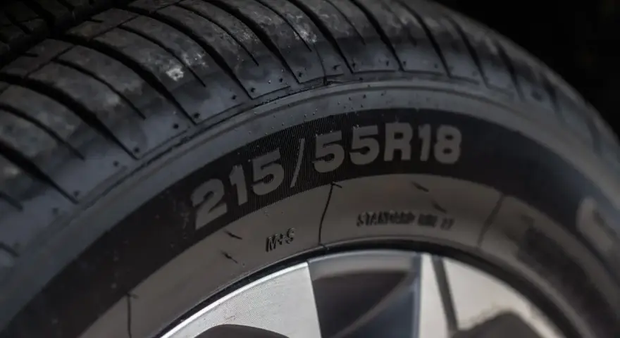 Zbliżenie na oponę z widocznymi oznaczeniami 215/55R18. To ważne oznaczenia opon, które informują o jej rozmiarze i konstrukcji.