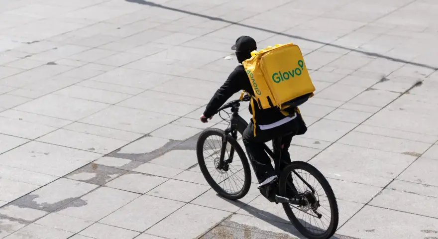 Kurier Glovo na rowerze z charakterystyczną żółtą torbą. Praca w dostawie to jego codzienne wyzwanie.