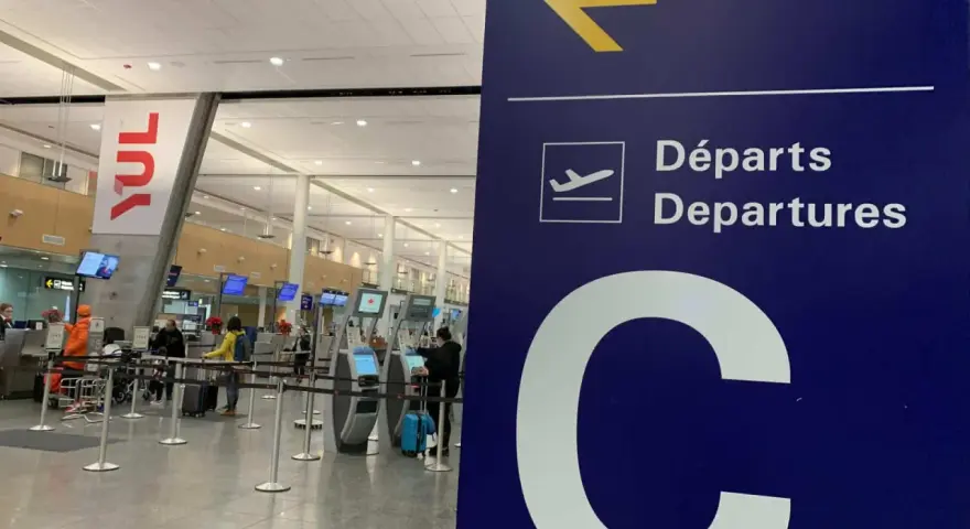 Tablica kierująca na lotnisku Montreal YUL, z napisem "Departures" i dużą literą "C".