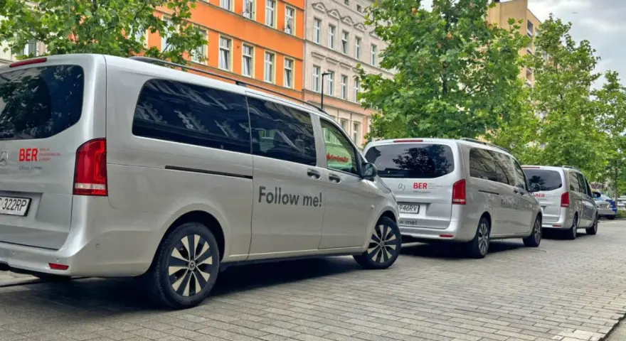 Srebrne vany z napisem "Follow me!" i logo BERLIN BRANDENBURG AIRPORT. Idealne, by dowiedzieć się, jak dojechać na lotnisko Berlin Brandenburg.