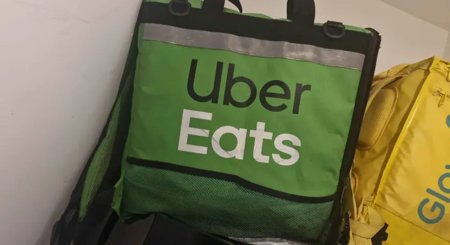 Zielona torba Uber Eats, obok żółtej torby Glovo. Taki widok może oznaczać potencjalne uber eats zarobki.