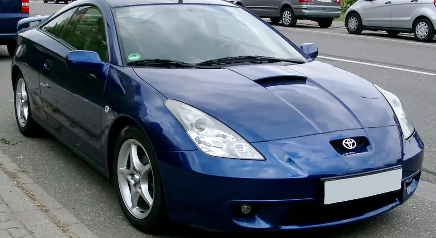 Błękitna Toyota Celica, jeden z najpiękniejszych aut, parkuje na poboczu drogi.